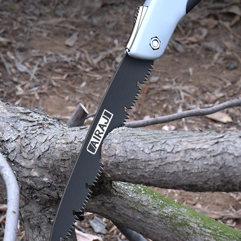 Close-up of a folding saw cutting through a tree branch.