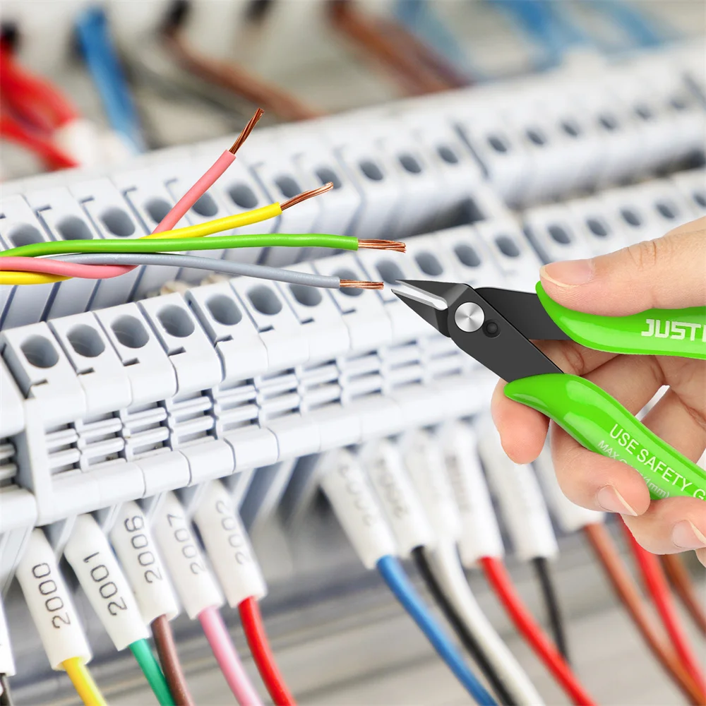 Hand using wire cutters on electrical panel with colorful wires.